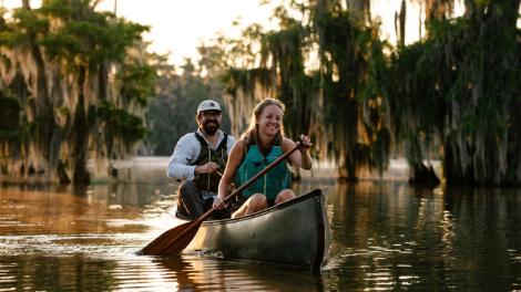 Couple canoeing alongside cypress trees on Lake Martin near Breaux Bridge, Louisiana Couple canoeing alongside cypress trees on Lake Martin near Breaux Bridge, Louisiana
