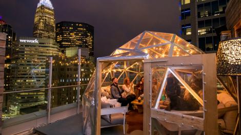 Disfrutando de la hora feliz en la azotea con vistas al centro de Charlotte en Merchant & Trade en Charlotte, Carolina del Norte