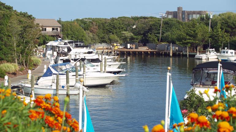Wooden boardwalks lined with trees wind throughout the intimate beach communities of Cherry Grove and The Pines on Fire Island.
