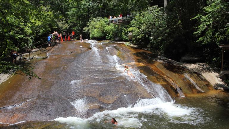 Swimmers sliding down the smooth-surfaced Sliding Rock boulder in Pisgah National Forest