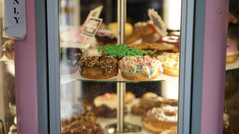 Rotierende Auslage mit buntem Süßgebäck bei Voodoo Doughnut