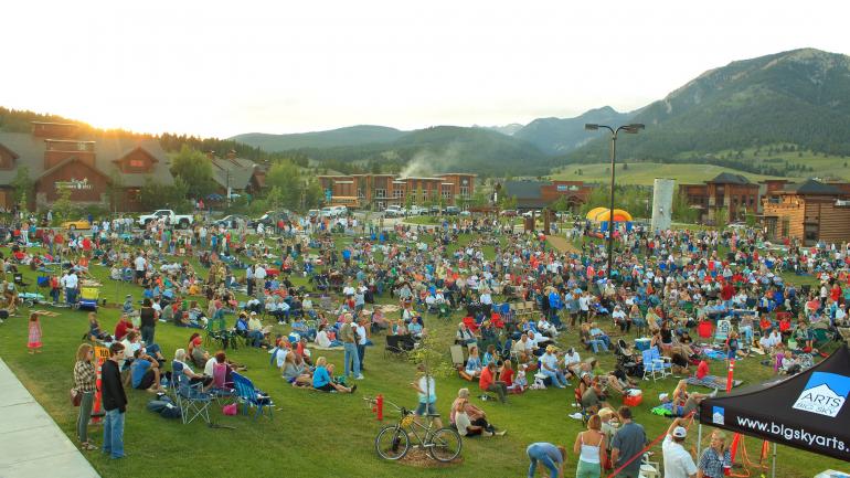 빅 스카이에서 산맥에 둘러쌓여 라이브 음악을 감상하는 사람들