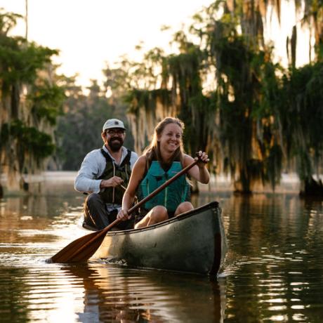 Casal durante um passeio de canoa junto a ciprestes no lago Martin próximo à Breaux Bridge, Louisiana