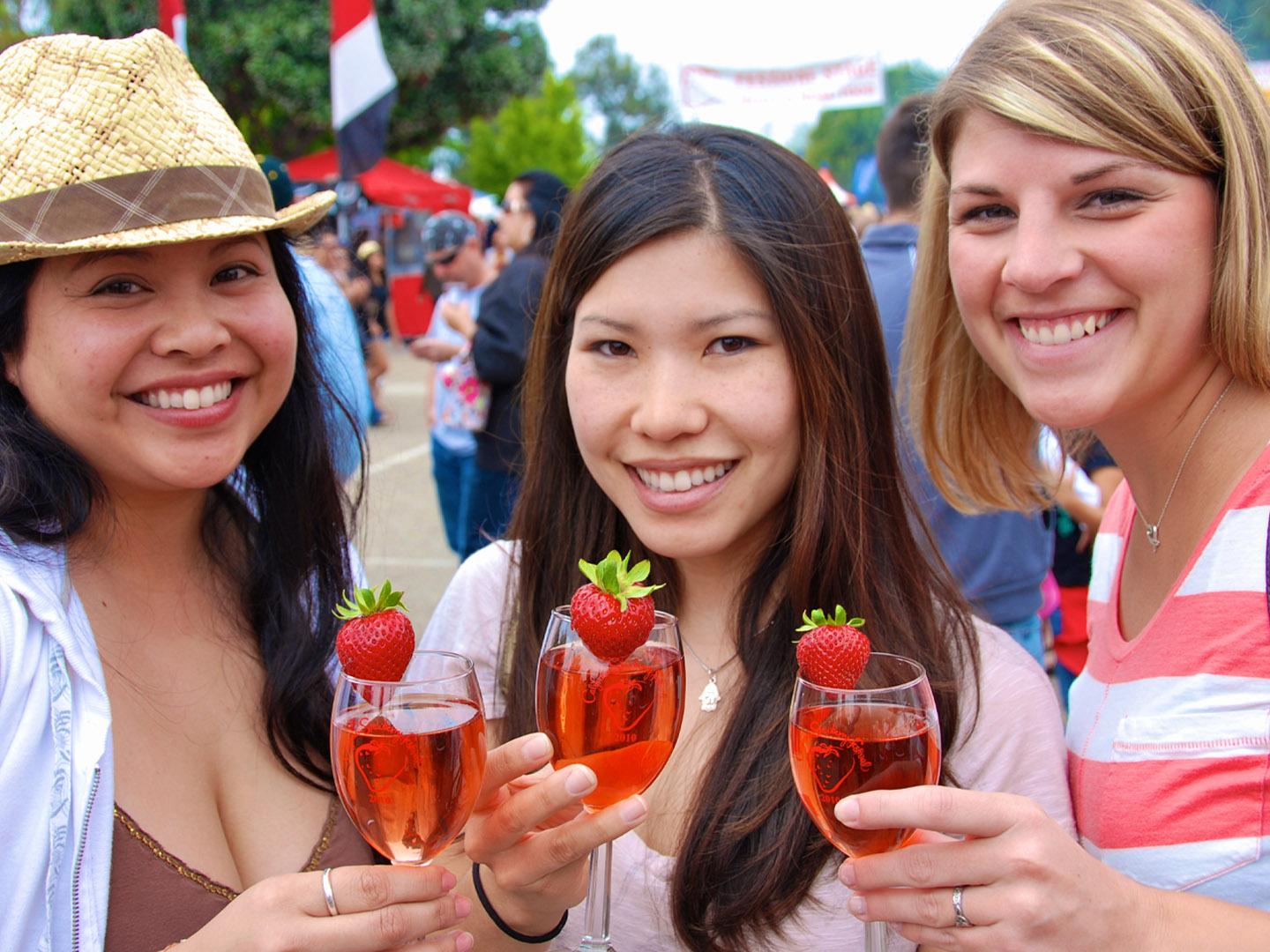 Friends enjoying a strawberry-flavored cocktail at the California Strawberry Festival in Oxnard