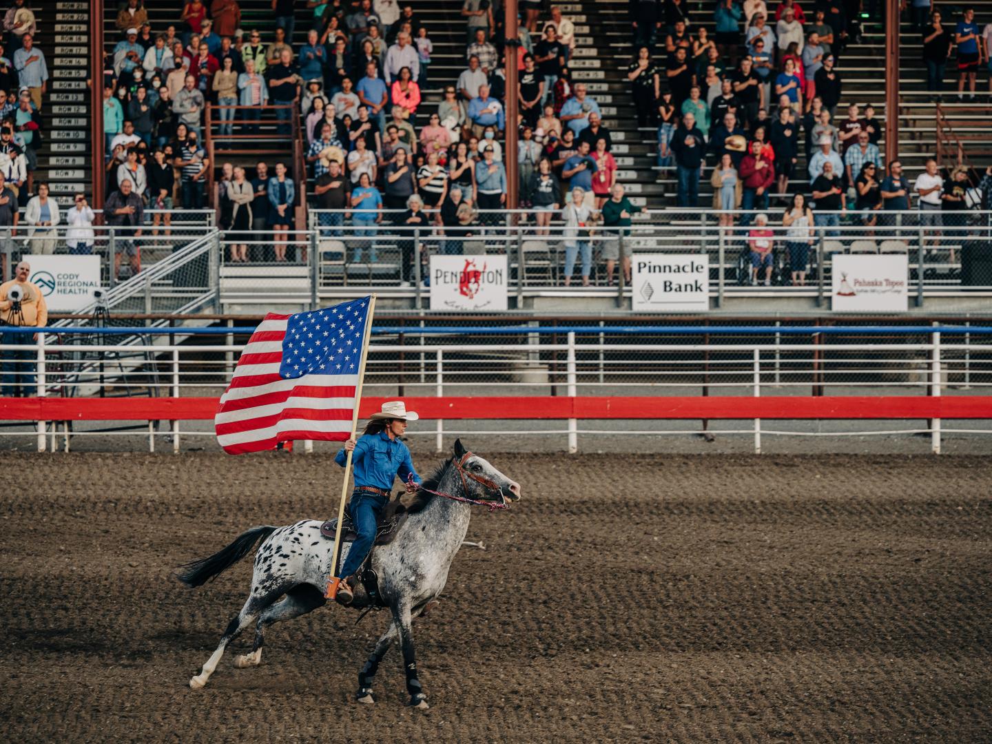 Rider carrying the American flag at the Cody Stampede Rodeo in Wyoming