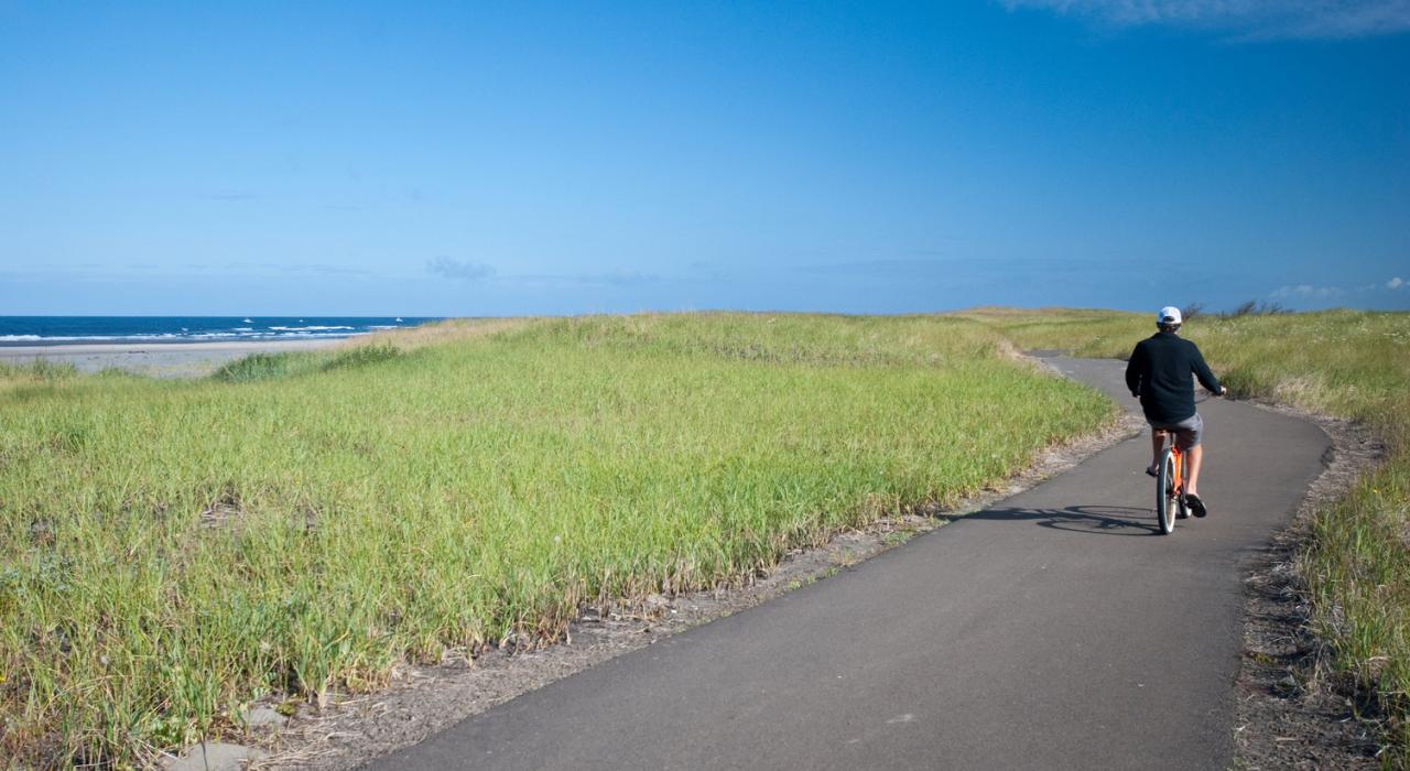 Hombre practicando ciclismo en el camino junto a la playa en Washington
