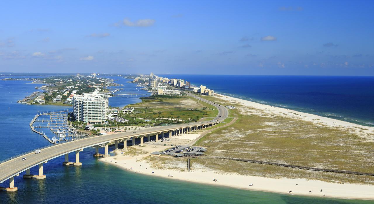 Roadway crossing over the water and alongside white-sand beaches in Gulf Shores, Alabama