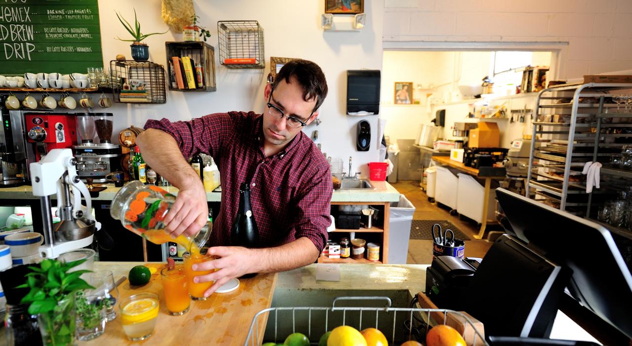 A barista pours juice at the modern diner, Milk Tooth