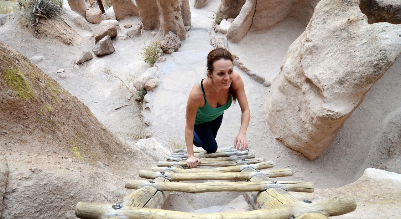 Climbing a ladder up to the ancient Anasazi cliff dwellings at Bandelier National Monument