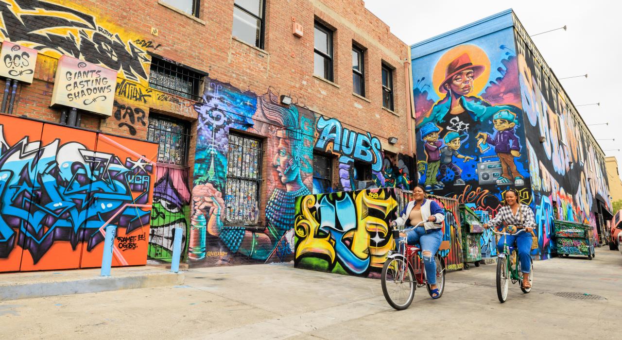 Cyclistes pédalant dans une rue aux murs couverts de peintures colorées dans le centre-ville de Santa Ana