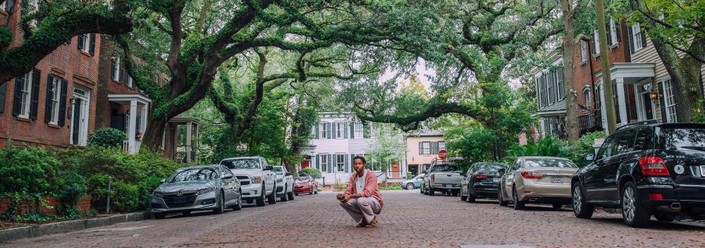 Tirando foto em uma rua de paralelepípedos em frente às mansões históricas e aos carvalhos em Savannah, Georgia